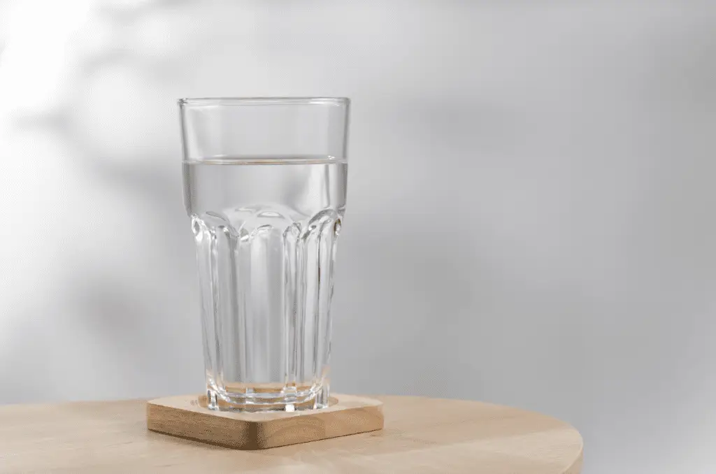 Un verre plein d'eau claire et pure sur un sous verre de bois