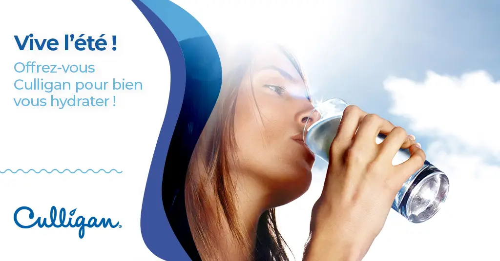 Une femme boit une grand verre d'eau pour s'hydrater en été