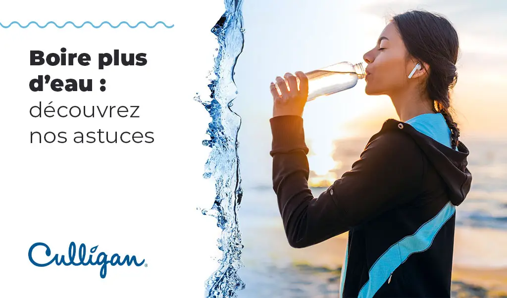 Une femme qui boit de l'eau devant l'océan, vêtu de vêtement d'exercice