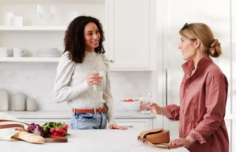 Deux femmes qui discutent dans une cuisine avec un verre d'eau