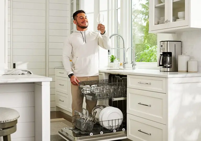 Un homme qui vide un lave-vaisselle, le tout est propre sans tache d'eau grâce au système de filtration