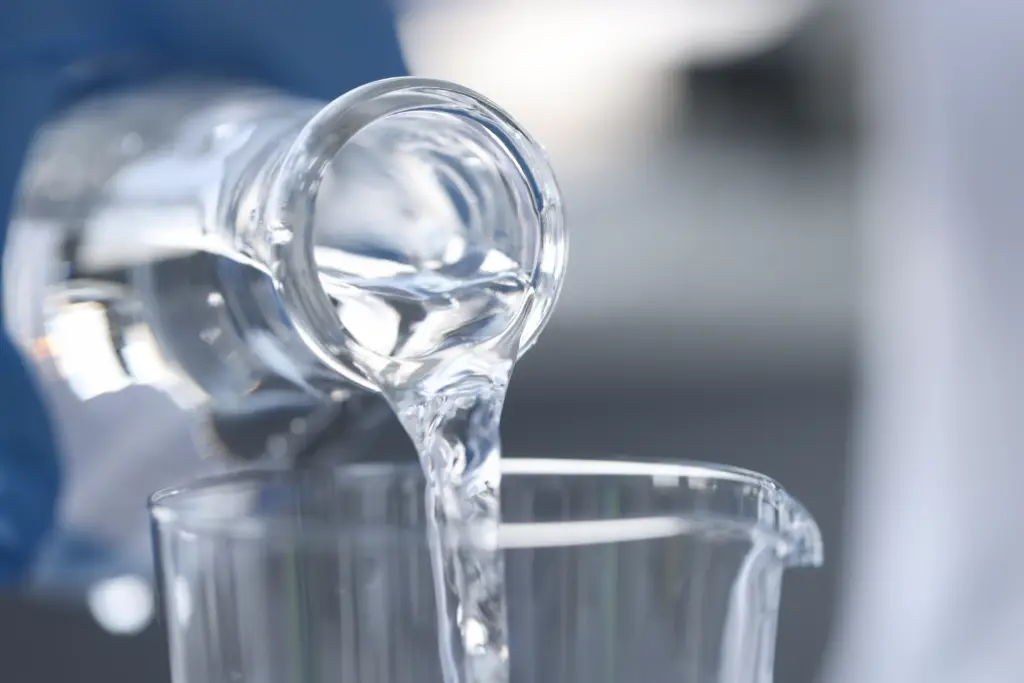 Image en rapproché d'une bouteille d'eau qui se verse dans un récipient de verre