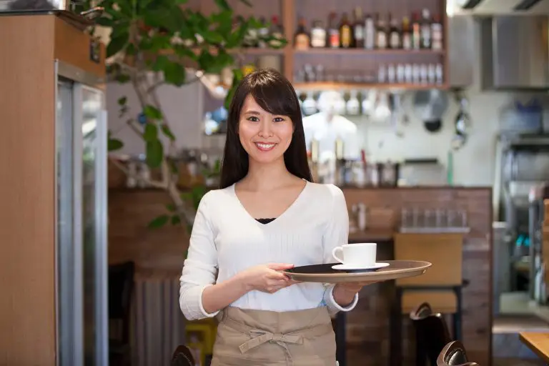 Une femme serveuse asiatique qui sert un café à un client