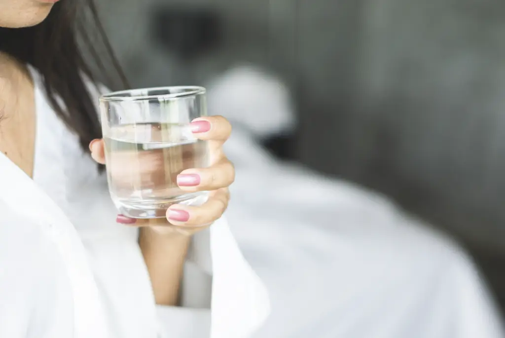 Une femme avec un verre d'eau clair et pure à la main