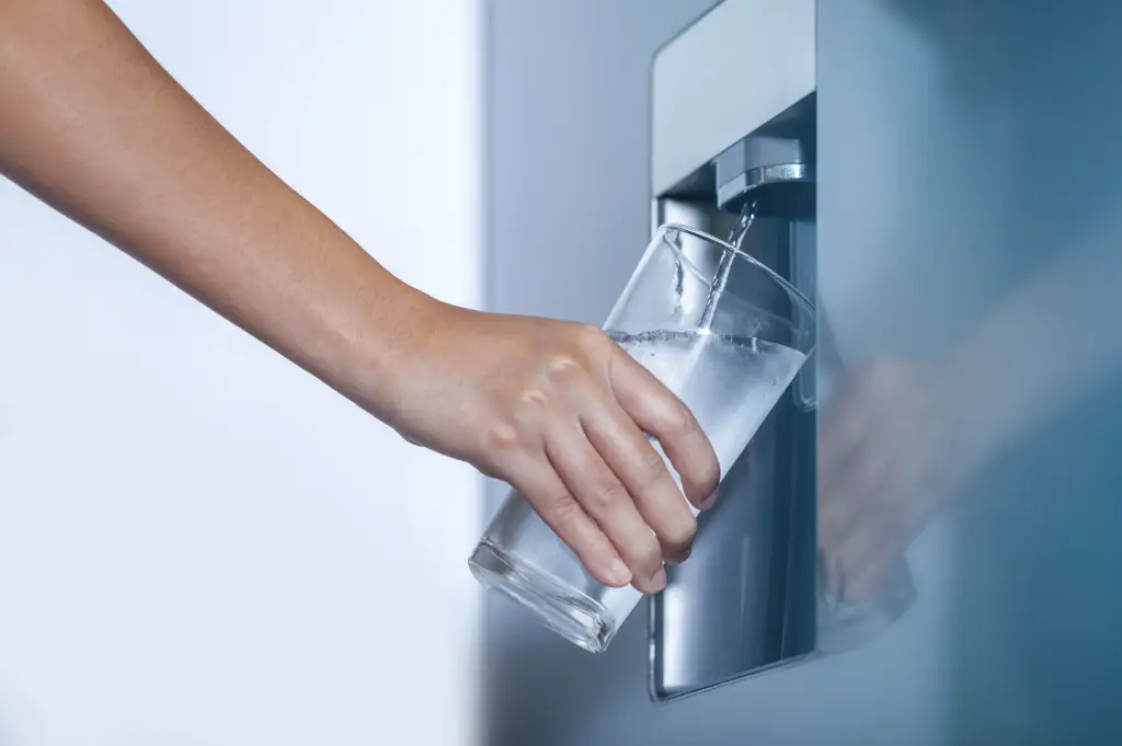 Femme qui remplie un verre d'eau avec une machine Culligan refroidisseur